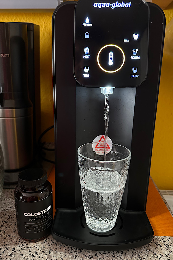 Wasser läuft aus Aqua-Global in ein Glas