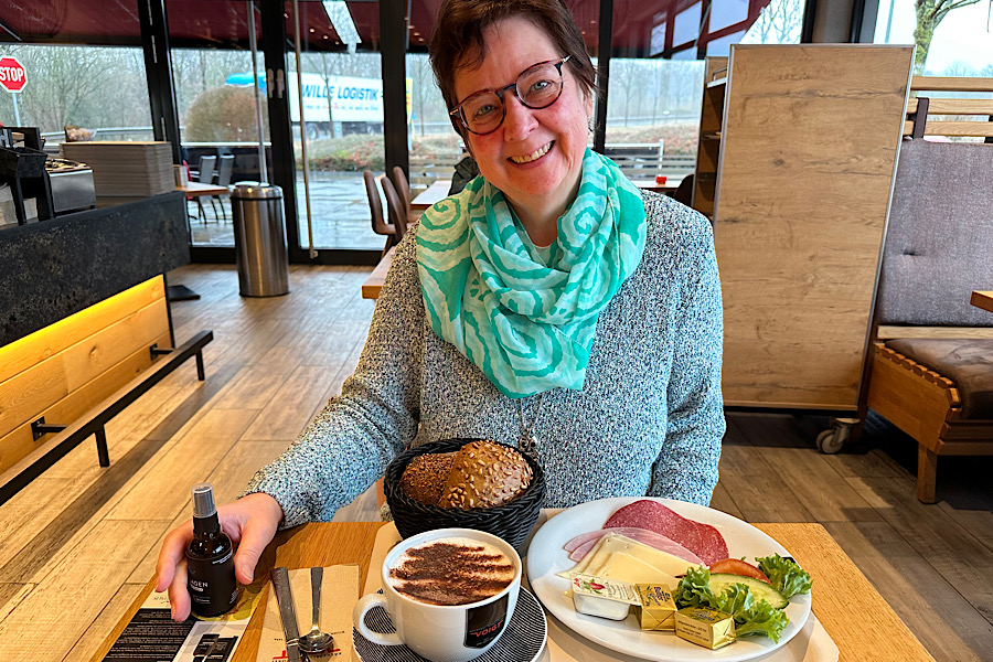 Britta sitzt beim Bäcker. Vor ihr steht Frühstück.